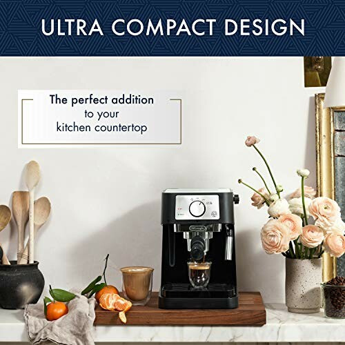 Compact espresso machine on kitchen countertop with flowers and utensils.